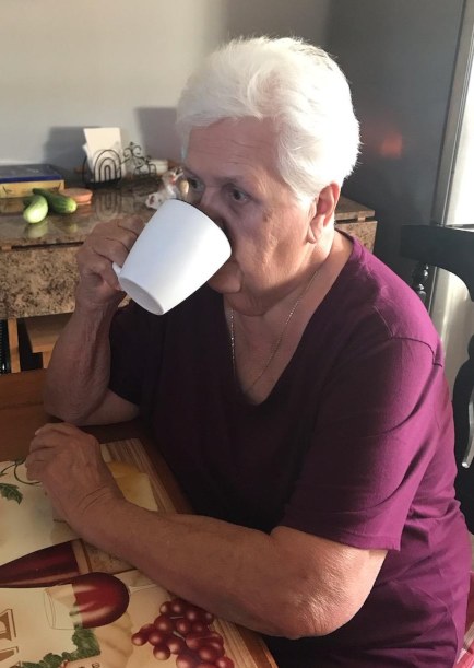 Elderly woman safely swallowing drink from mug